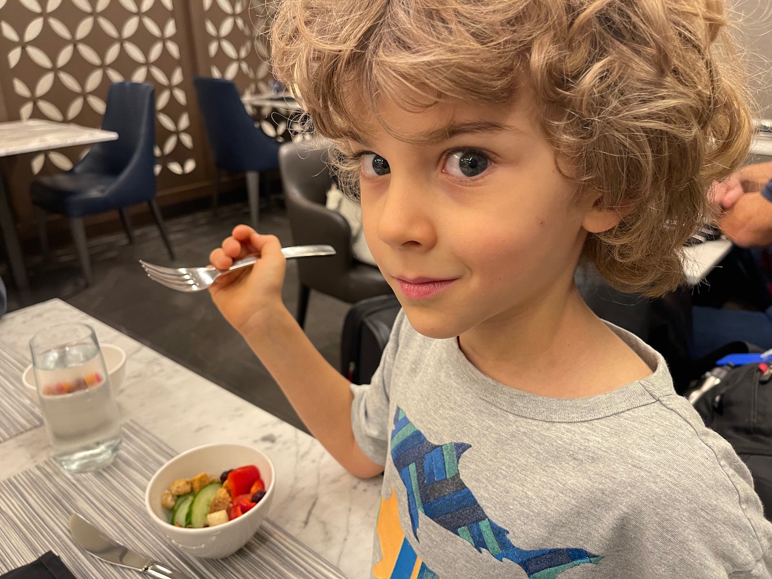 a boy holding a fork and a bowl of fruit