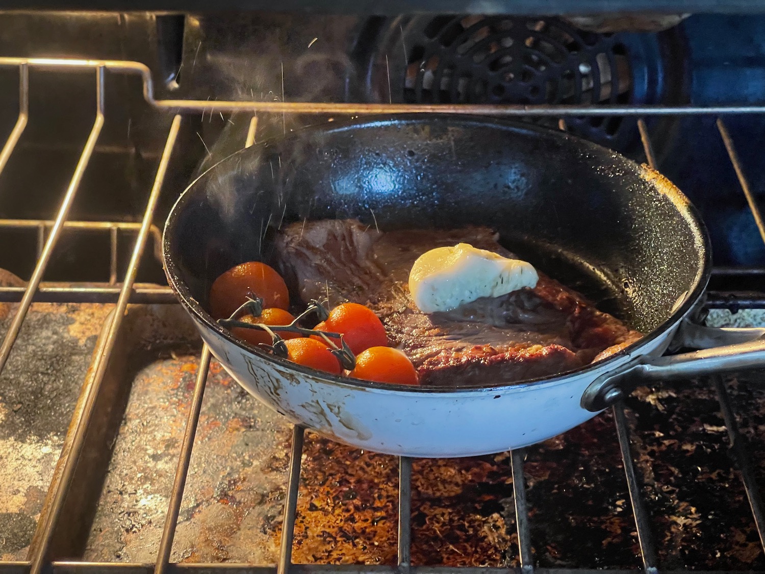 a meat and tomatoes cooking in an oven