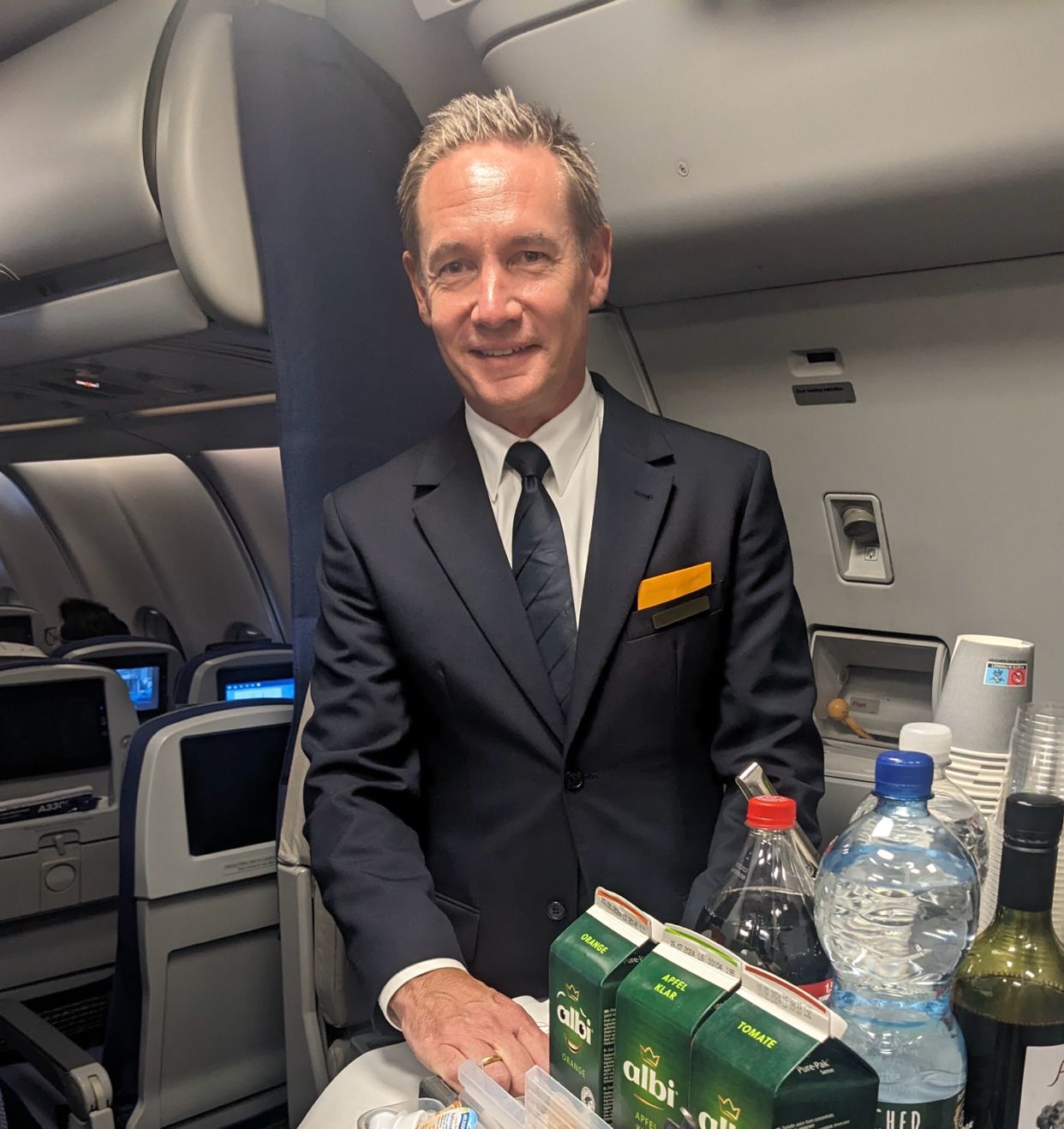 a man in a suit and tie standing in an airplane