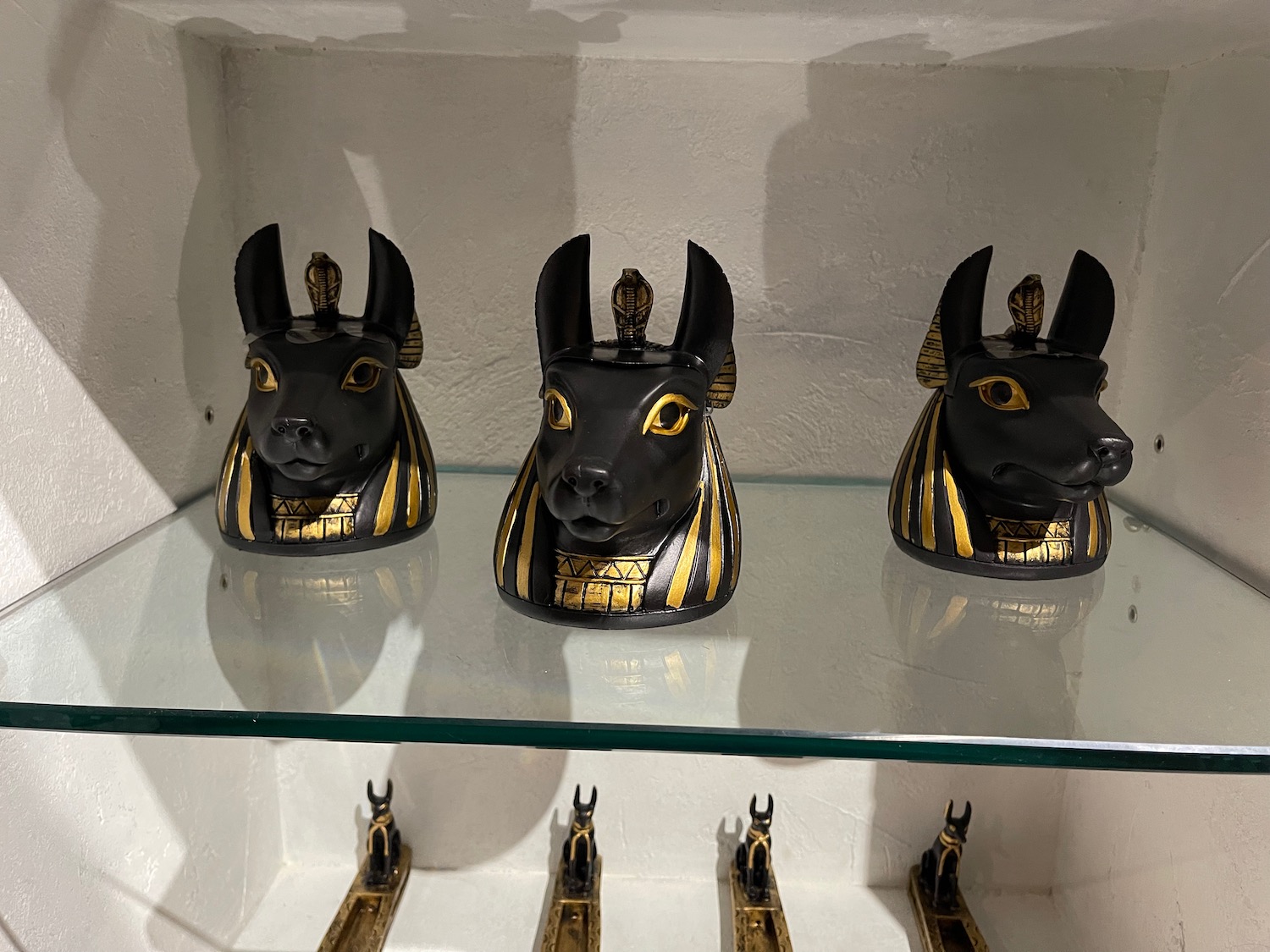 a group of black and gold statues on a glass shelf