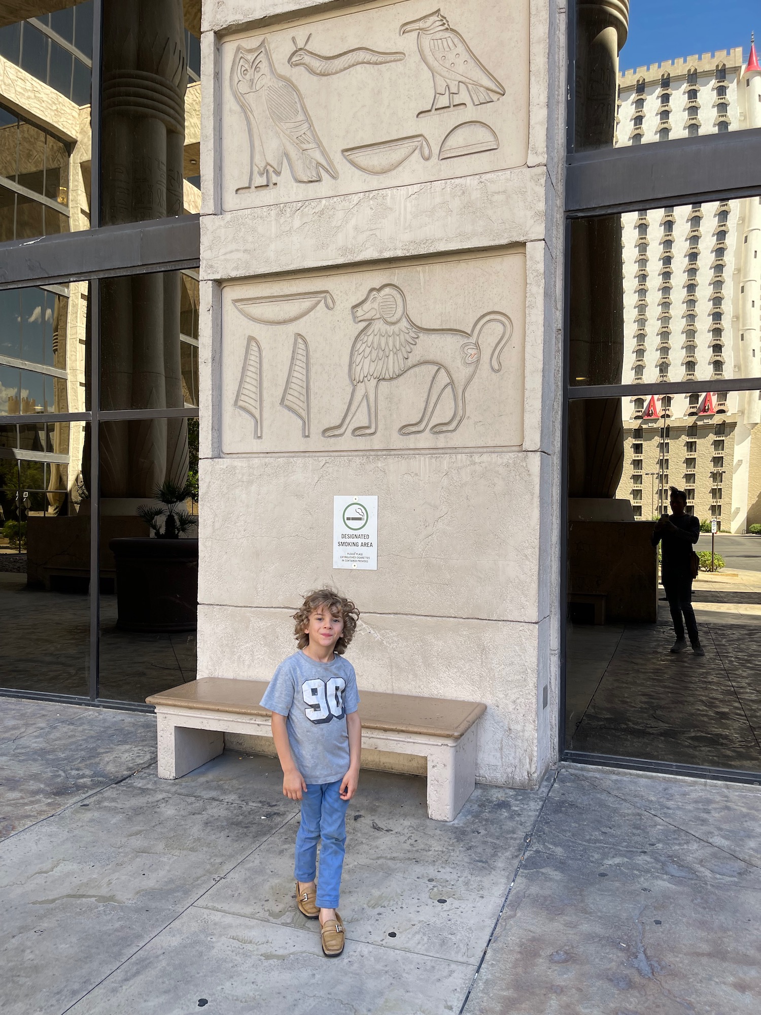 a boy standing in front of a building with a stone wall