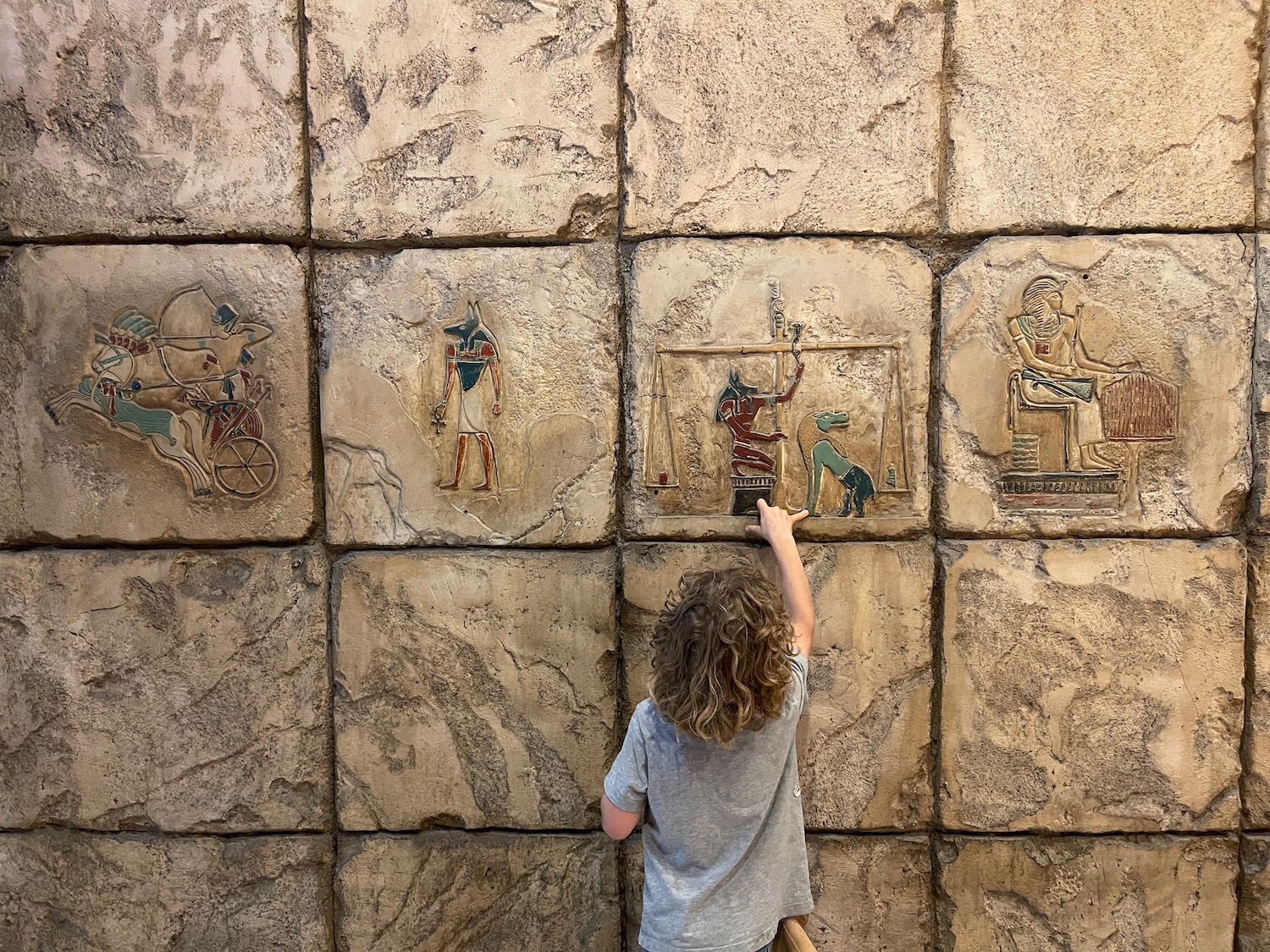 a child touching a wall with ancient egyptian art