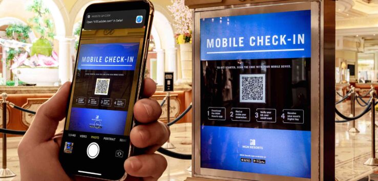 a hand holding a phone next to a check in machine