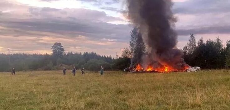 a group of people standing in a field with a large fire