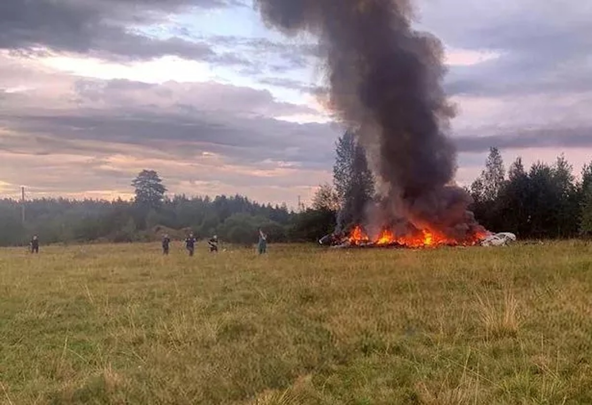 a group of people standing in a field with a large fire