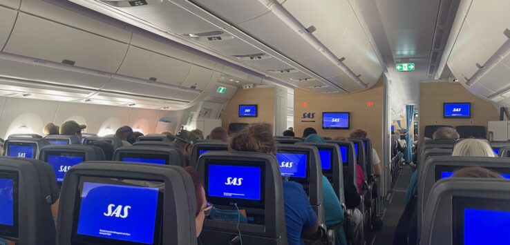 a group of people sitting in an airplane with monitors