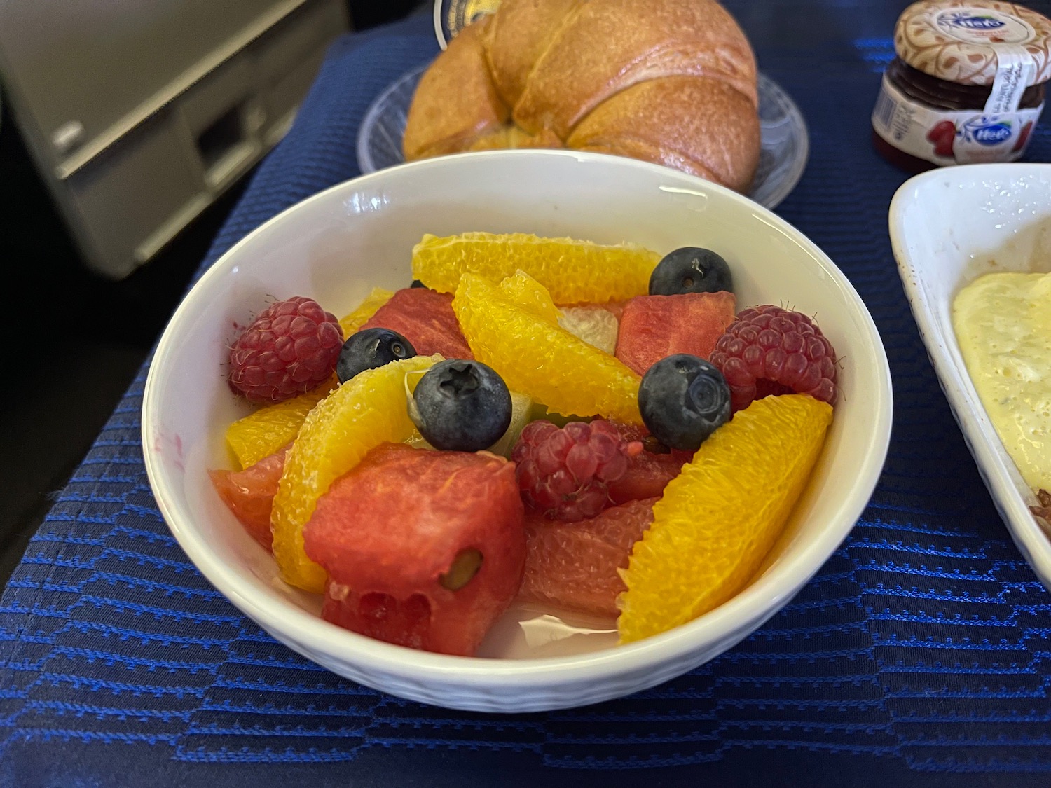 a bowl of fruit and a croissant