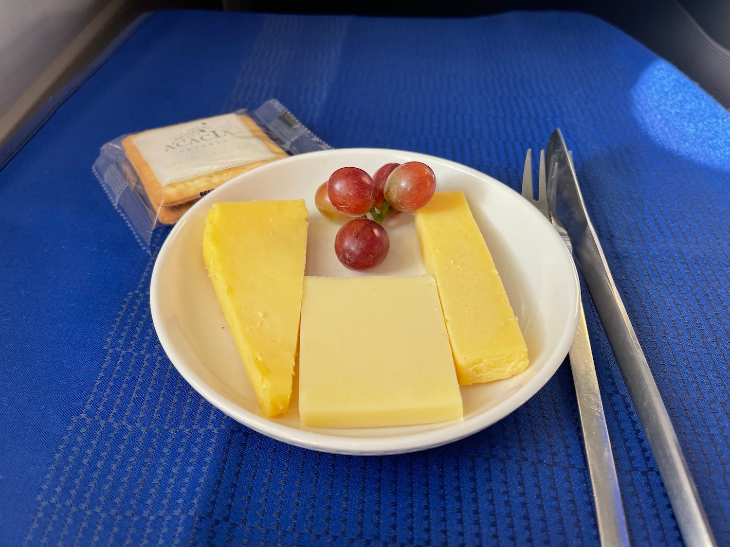 a plate of cheese and grapes on a blue place mat