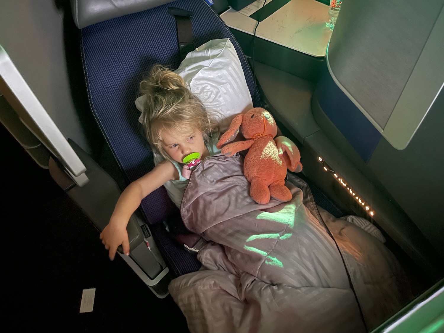 a girl lying in a bed with a stuffed animal