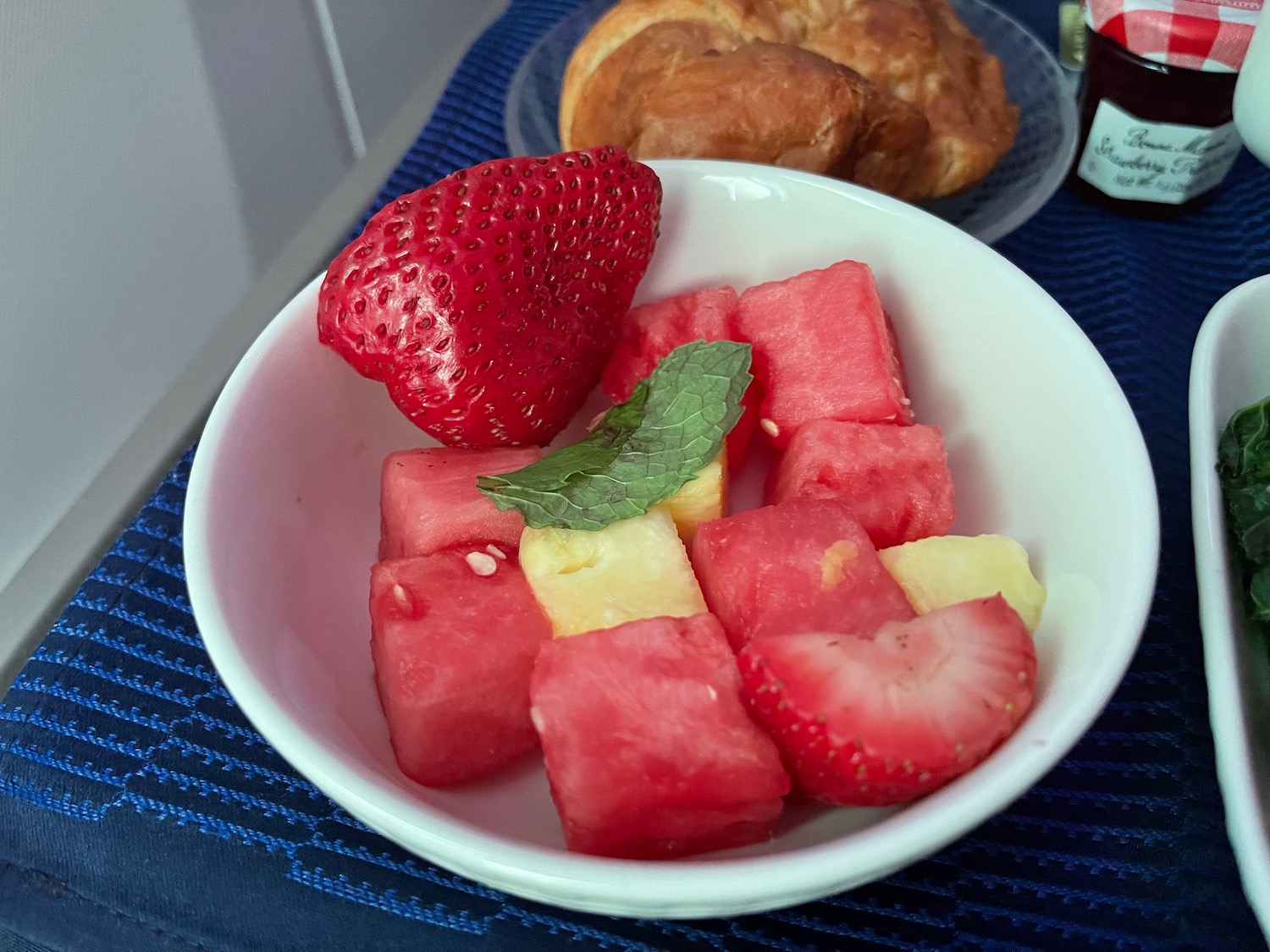 a bowl of fruit and a croissant