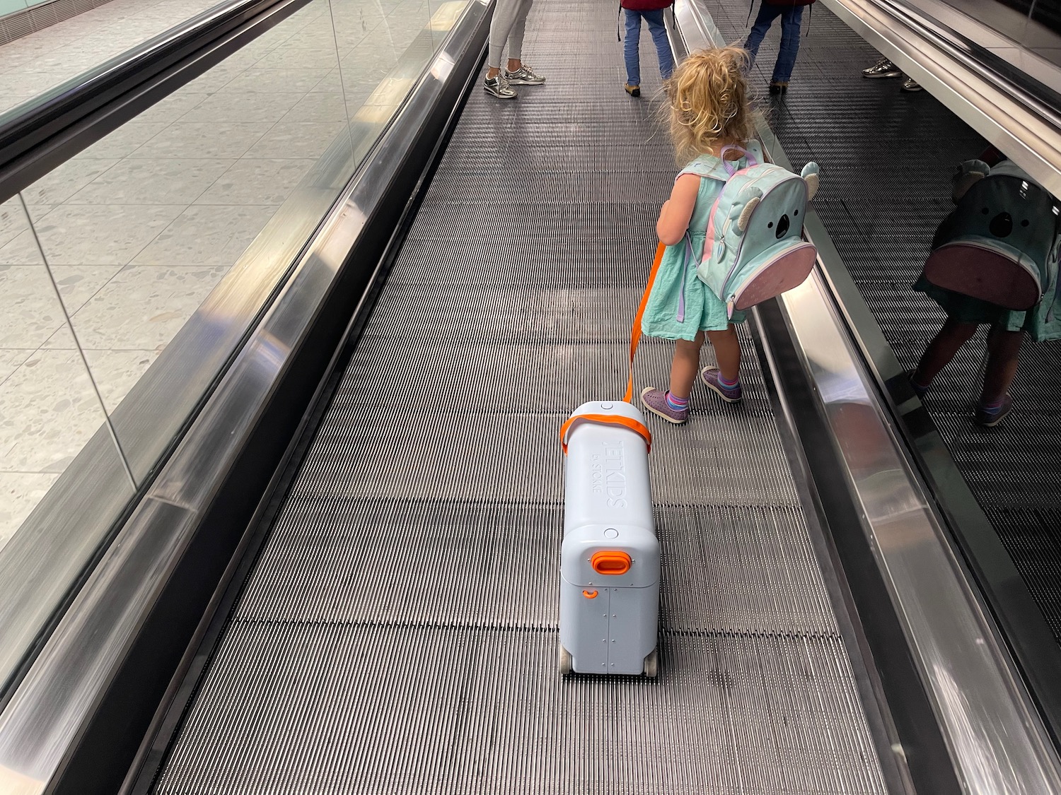 a child with a luggage case on an escalator