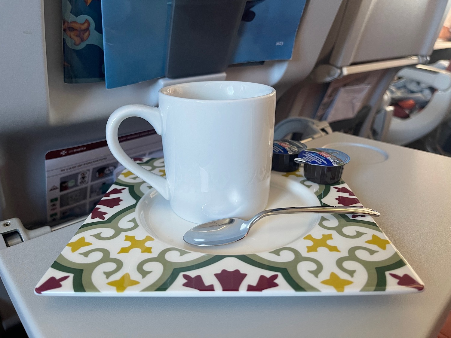 a white mug and spoon on a plate