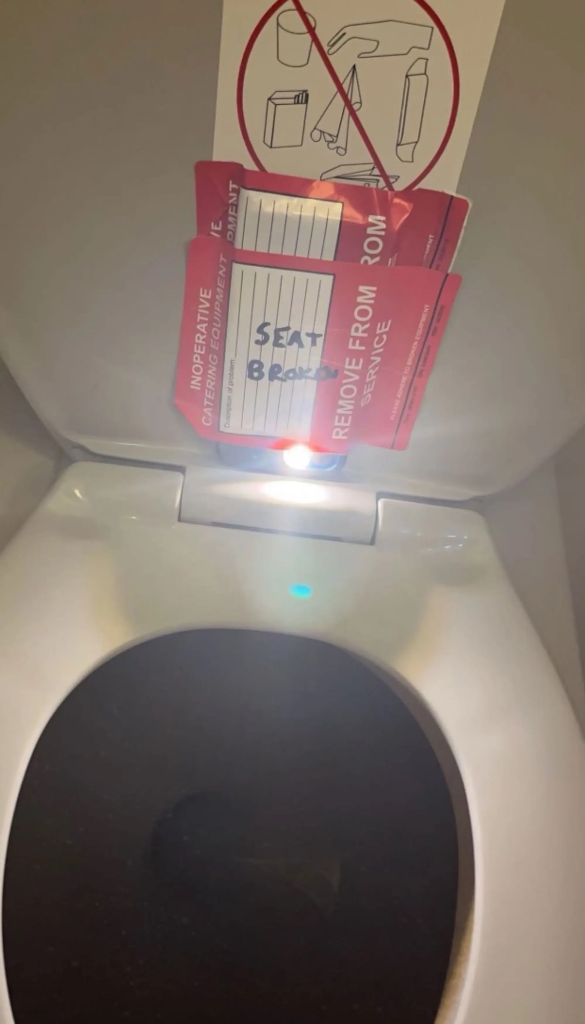 a toilet with red tickets on the lid