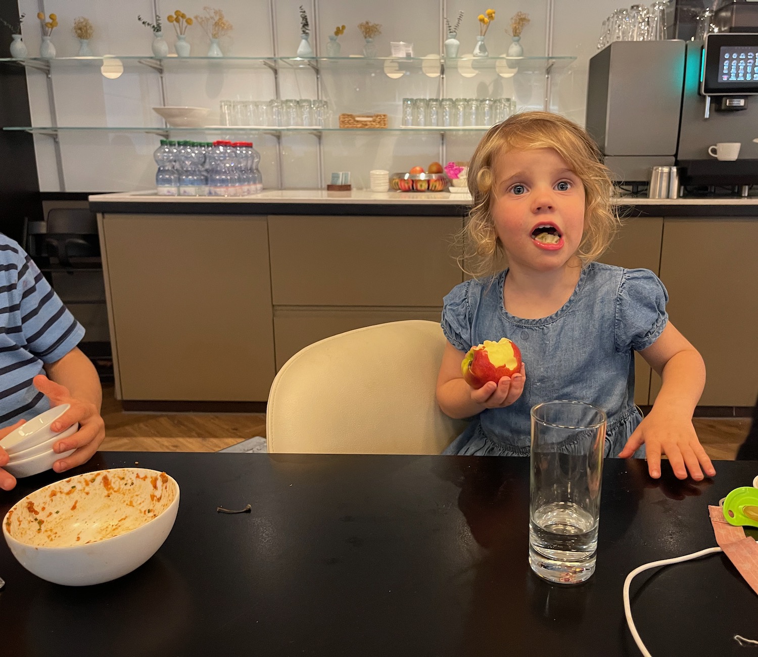 a boy and girl sitting at a table eating an apple