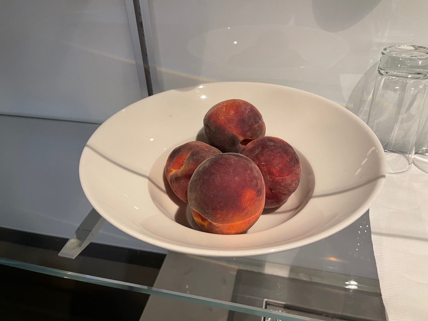 a plate of peaches on a glass shelf