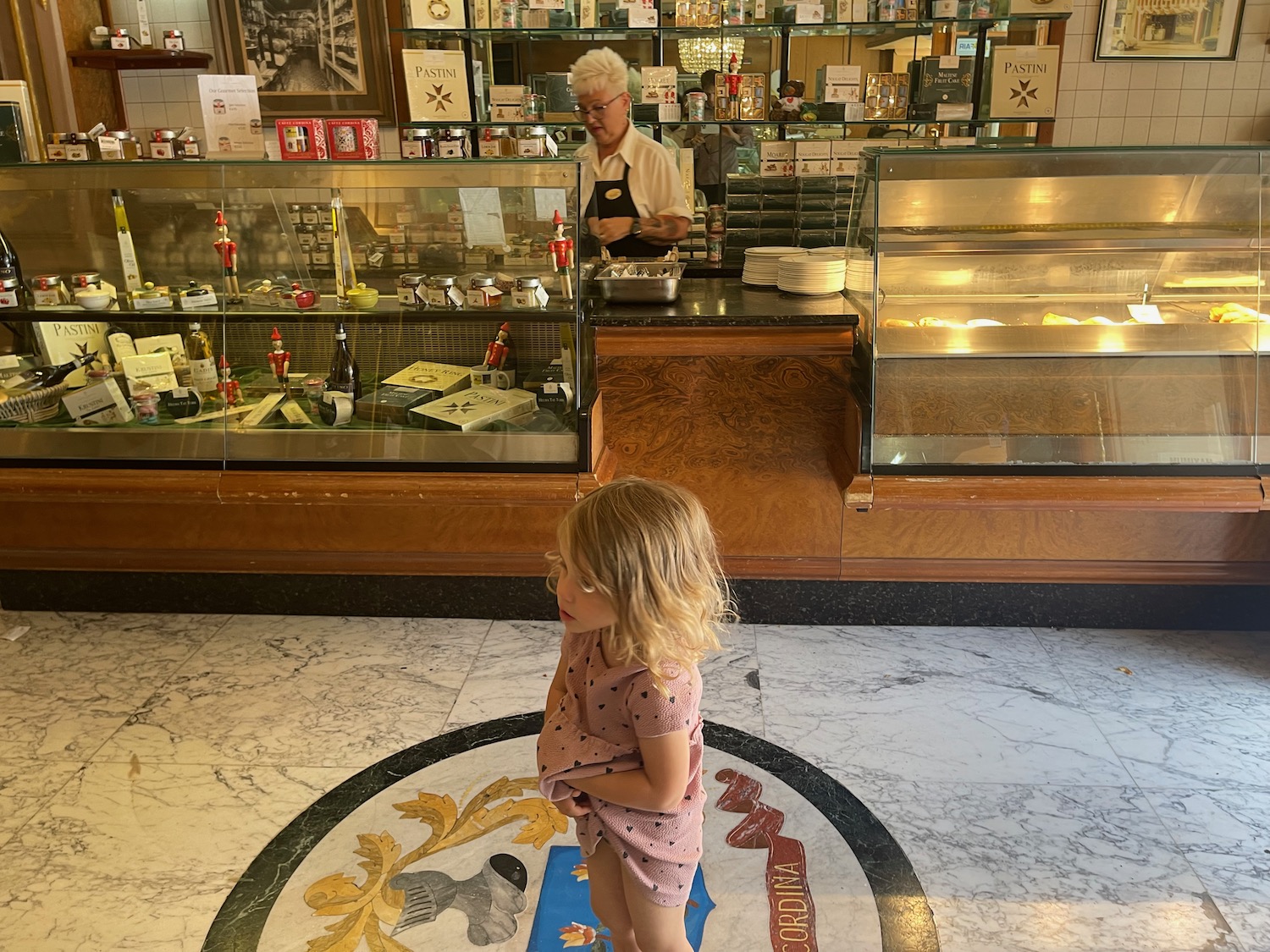 a girl standing in front of a counter with a man behind her