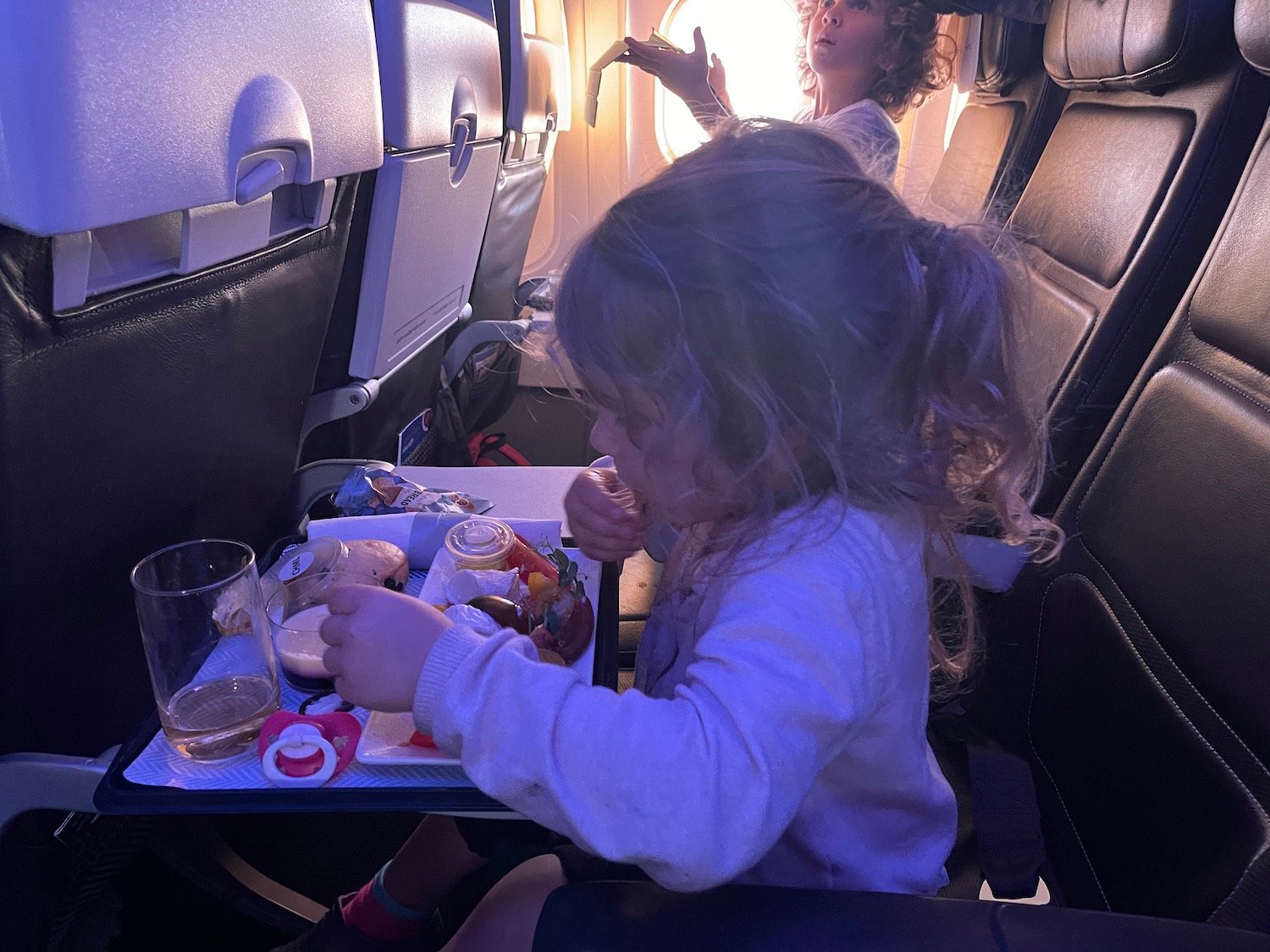 a child eating on a tray in an airplane