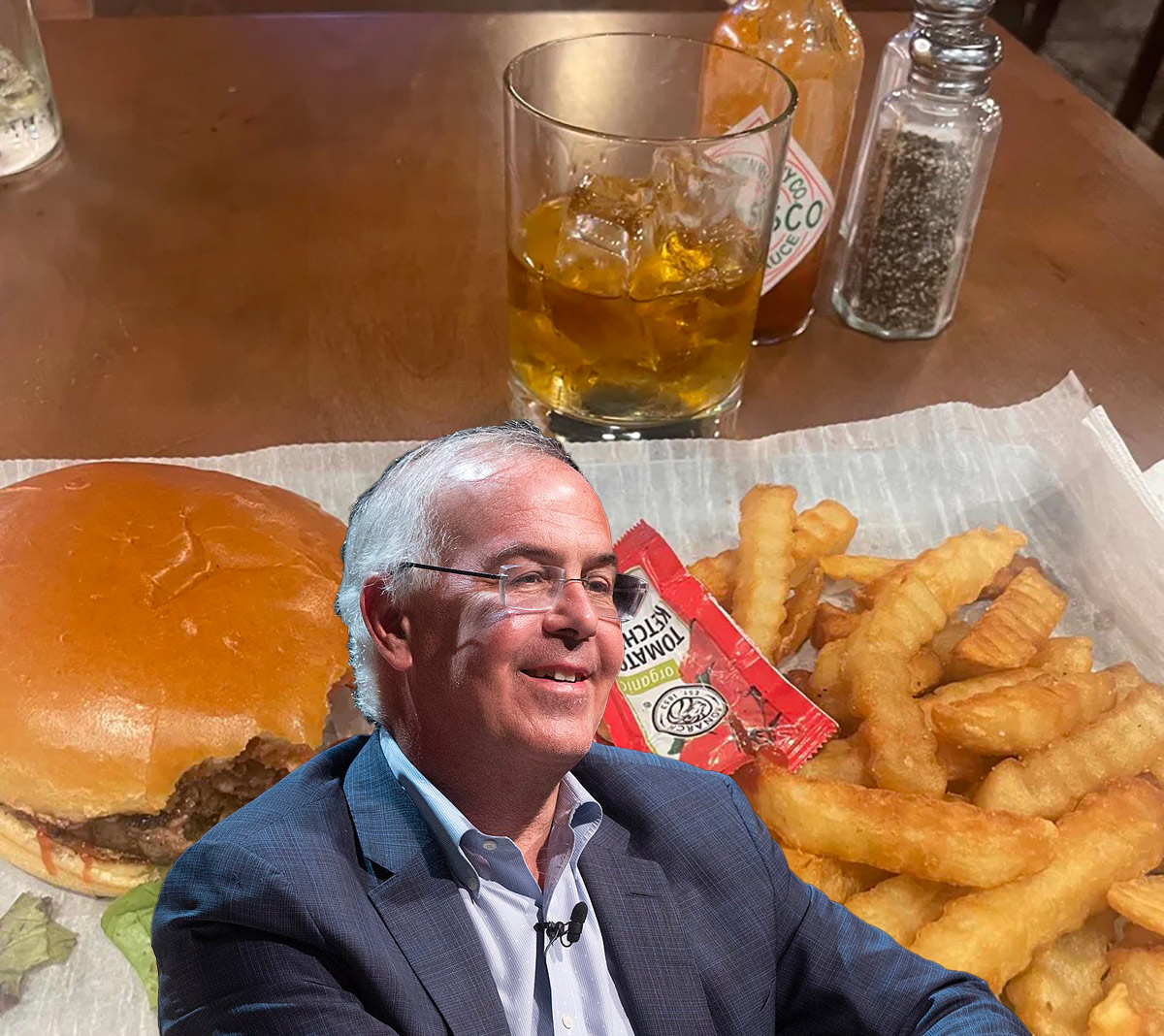 a man sitting at a table with a hamburger and fries