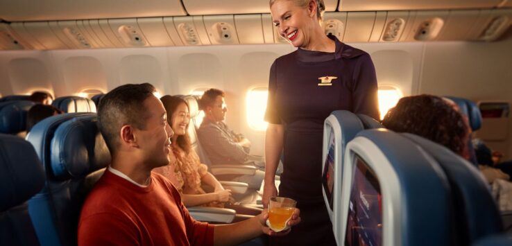 a woman serving drinks to a man on an airplane
