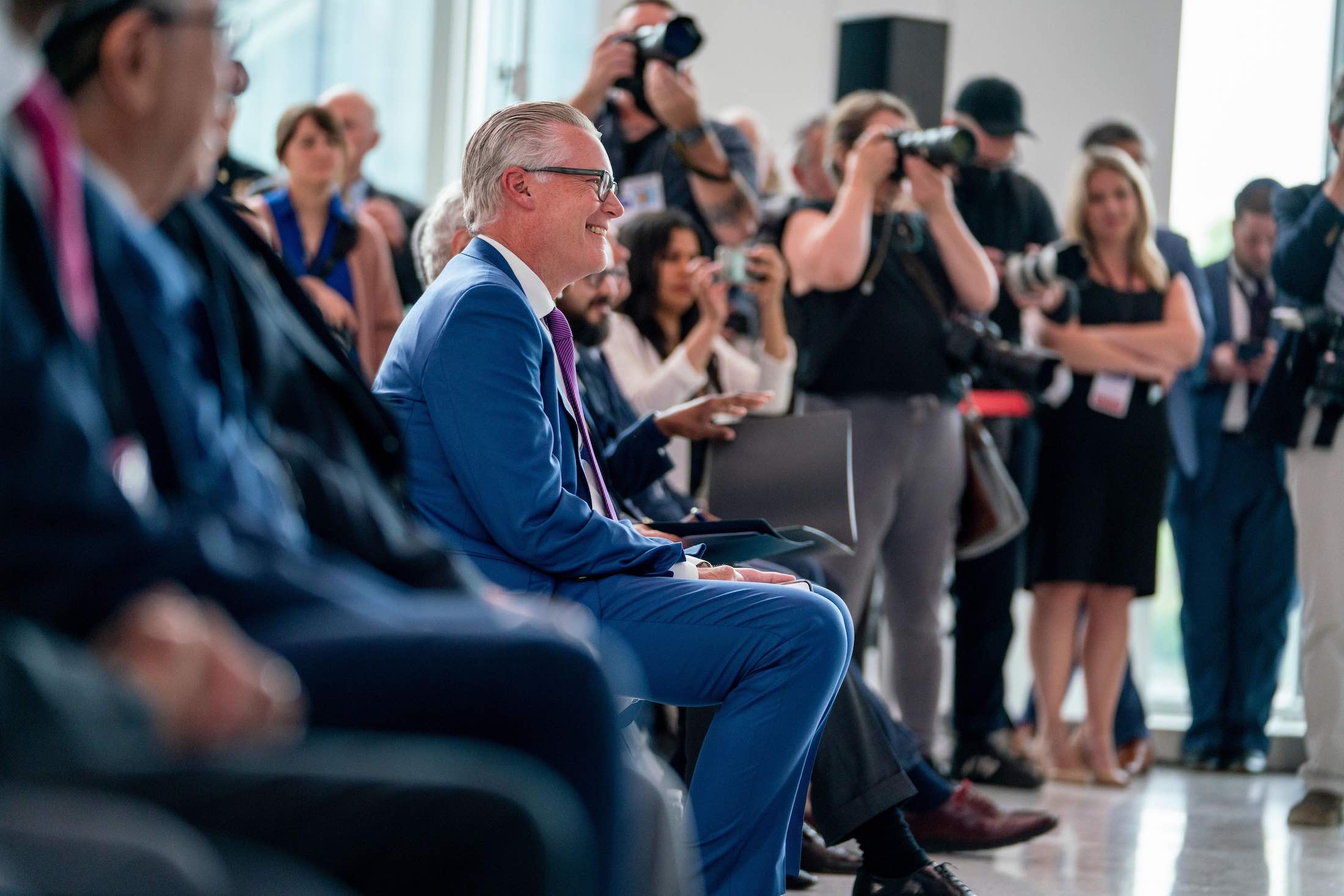 a man in a suit sitting in a crowd