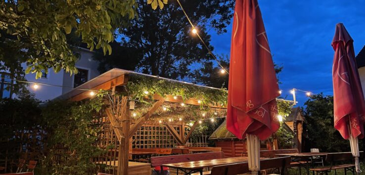 a patio with a red umbrella and chairs