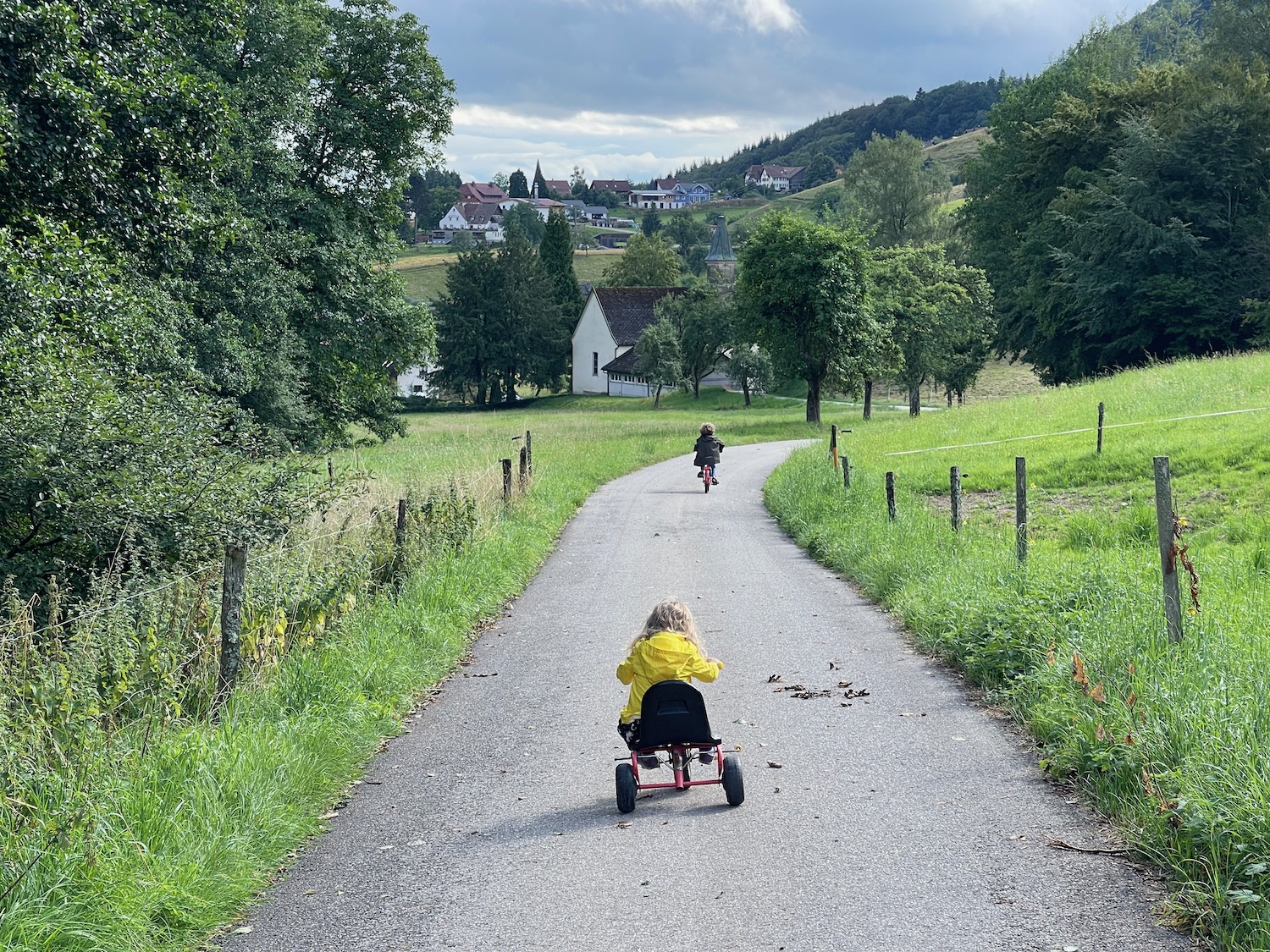 a child riding a tricycle on a path with a man riding a bike