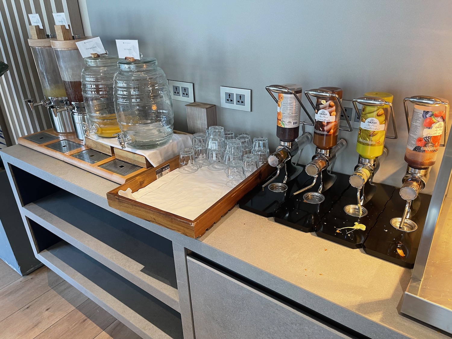 a group of glasses and a drink dispenser on a counter
