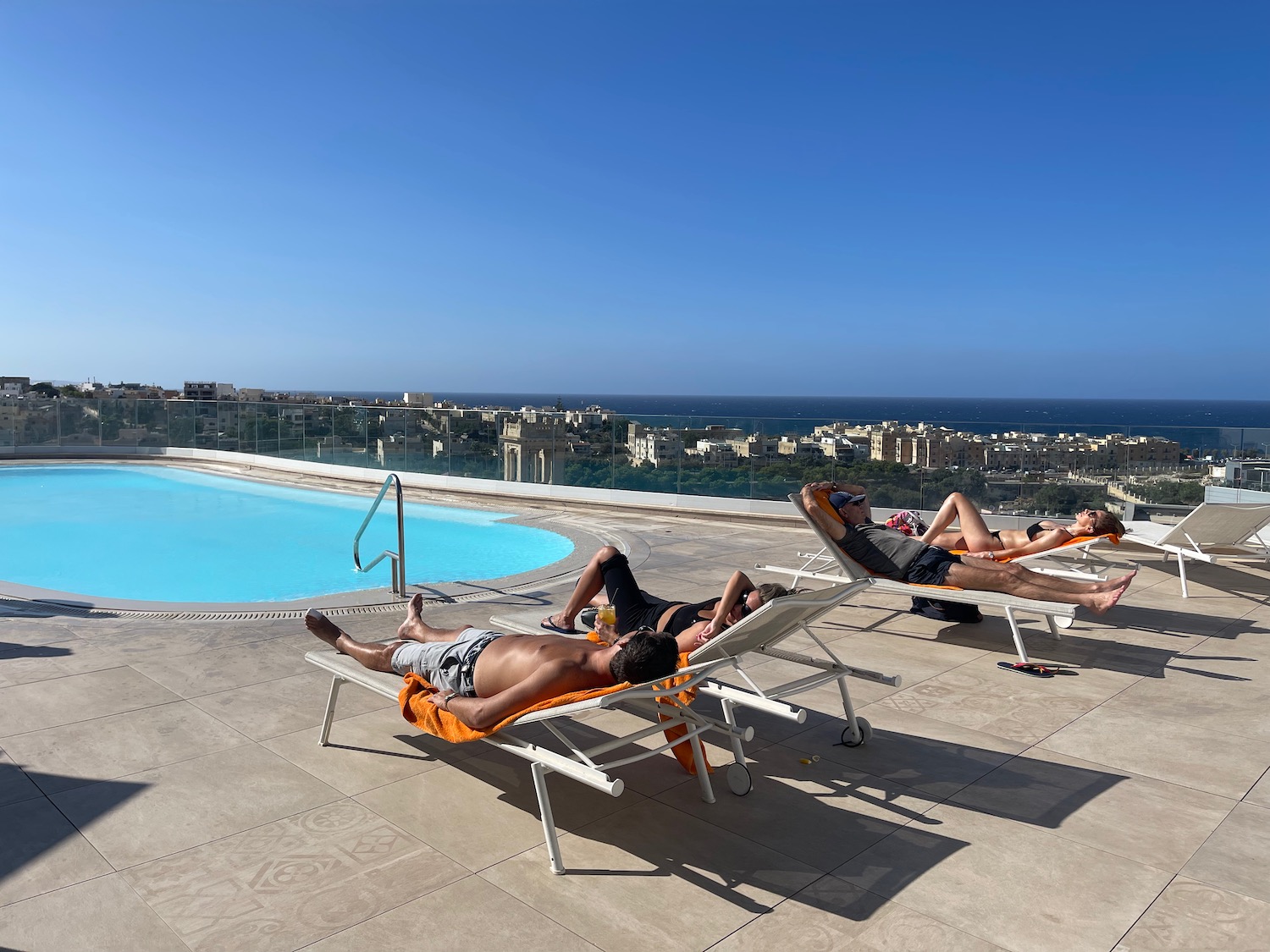 people lying on lounge chairs by a pool