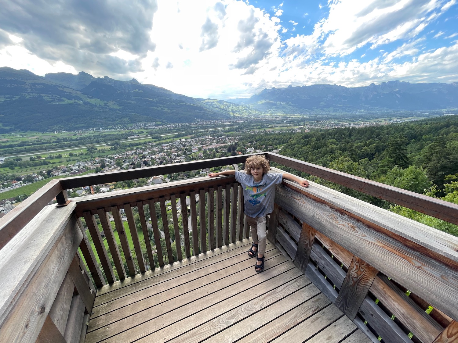 a child standing on a deck overlooking a valley