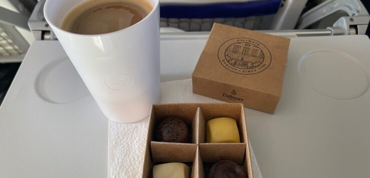 a cup of coffee and chocolates on a table