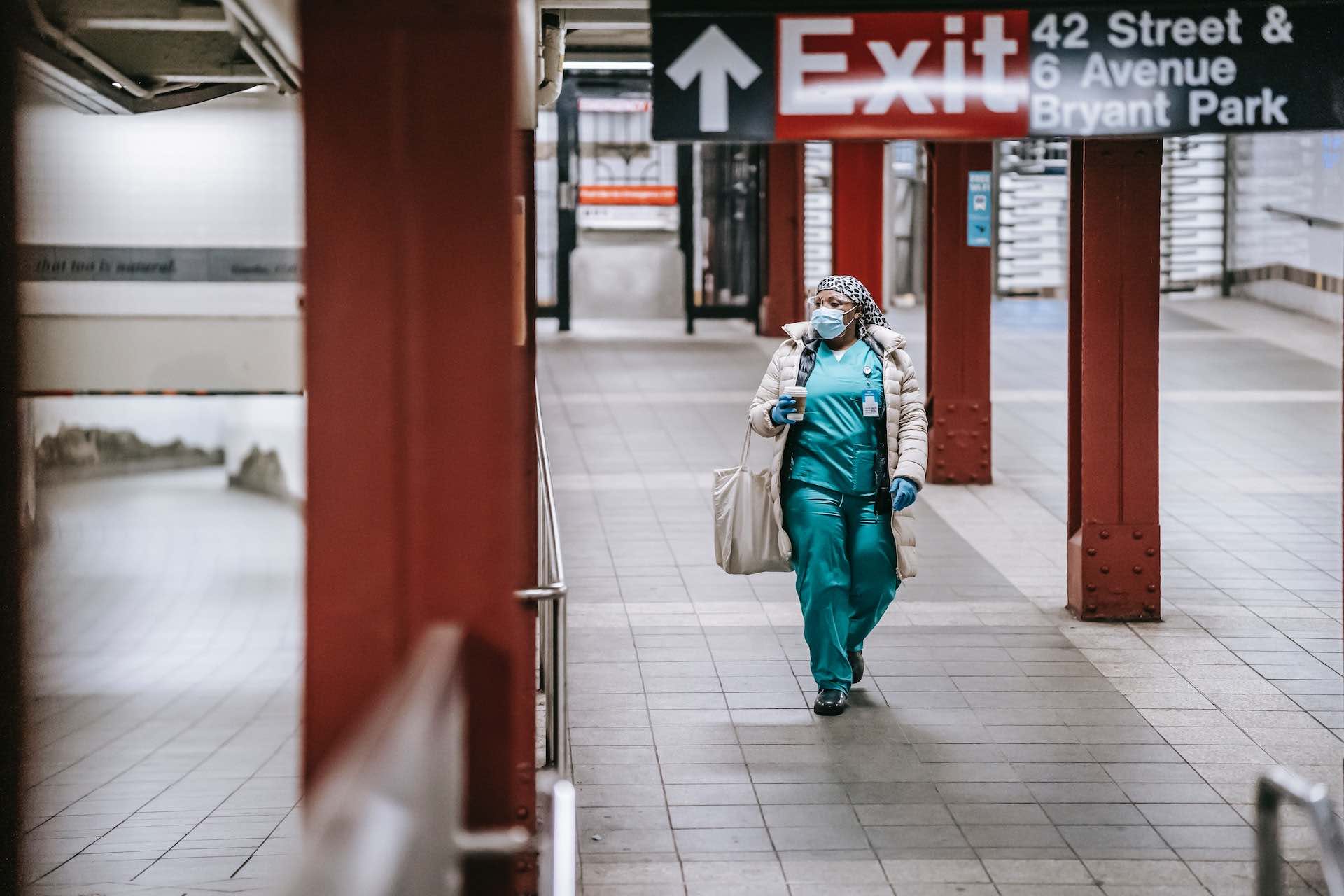 a woman wearing a face mask and a mask walking down a walkway