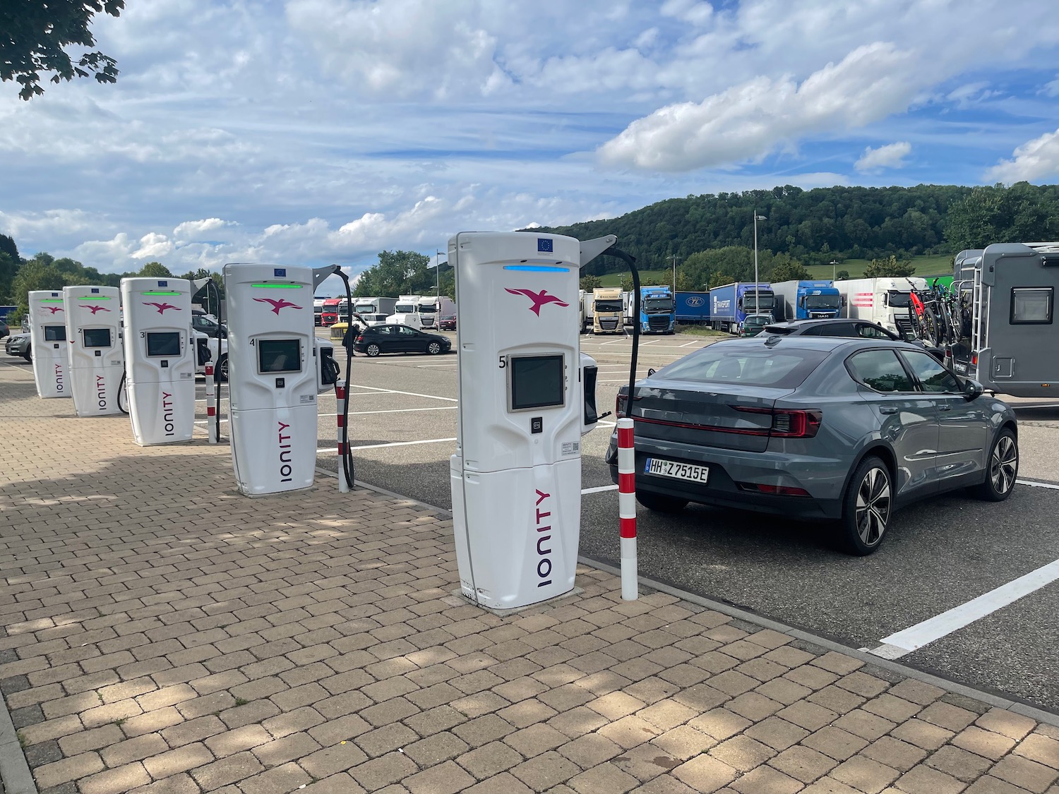 a group of white gas pumps next to a grey car