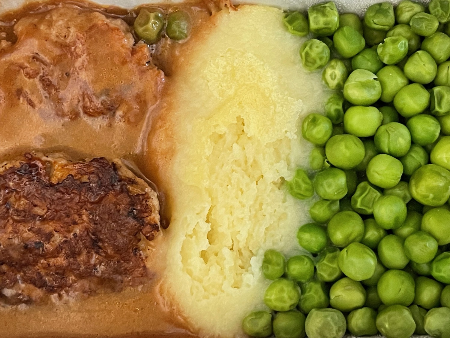 a plate of food with peas and meatballs