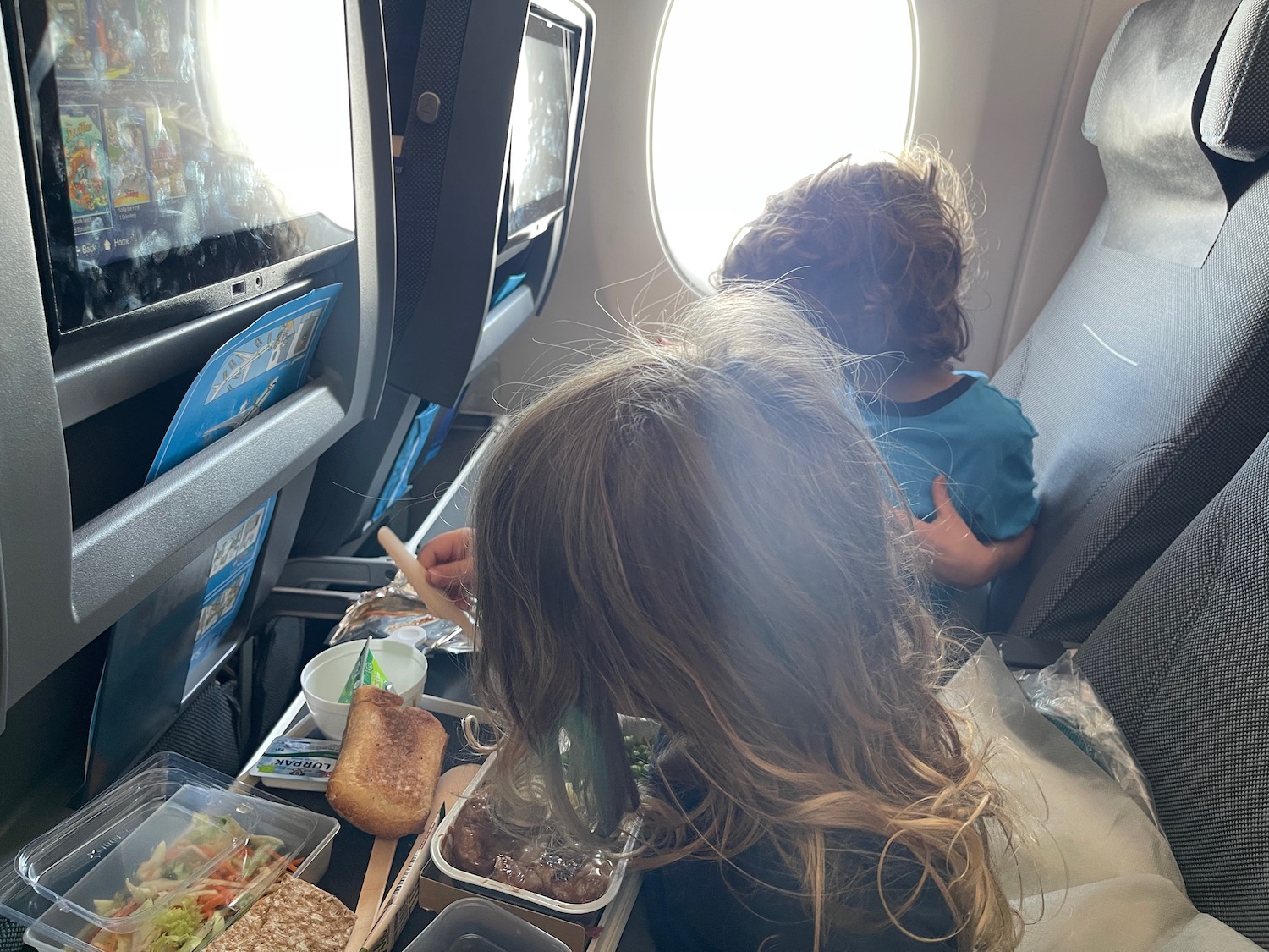 a woman and child eating on an airplane