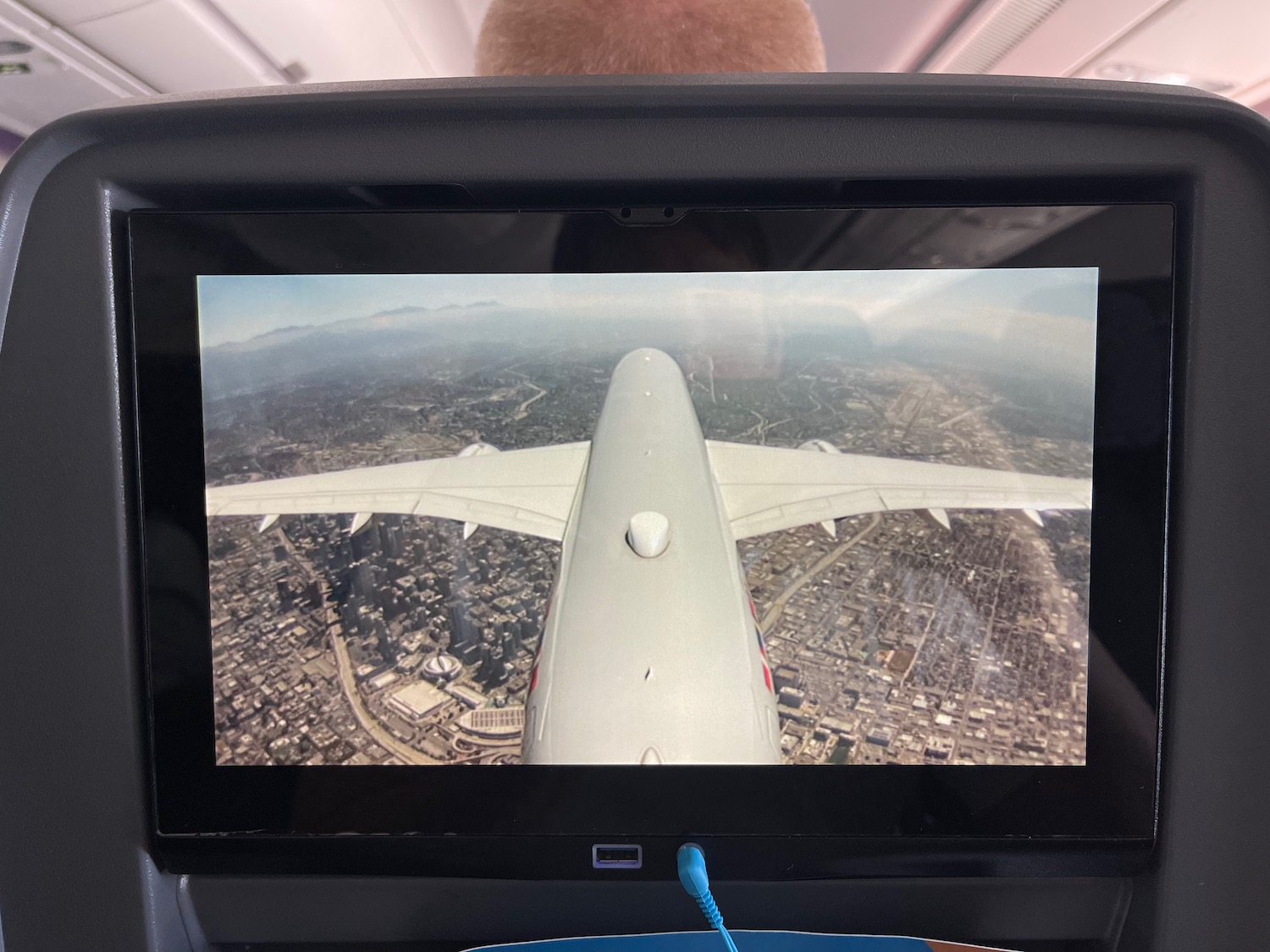 a screen with a plane wing and a city in the background