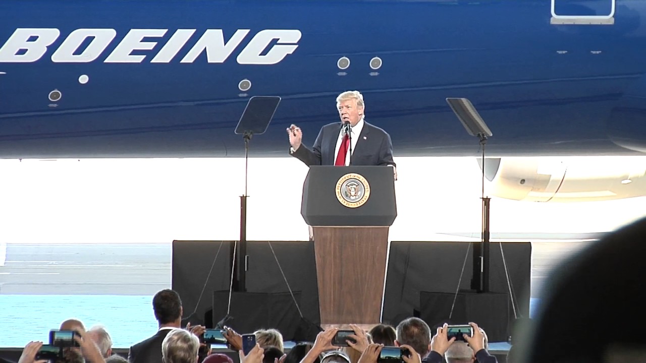 a man standing at a podium with a microphone and a crowd of people