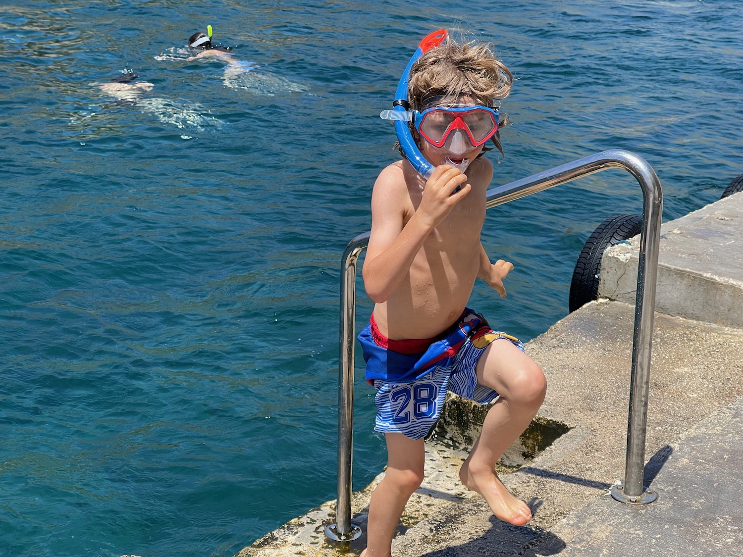 a boy wearing snorkeling gear and standing on a dock