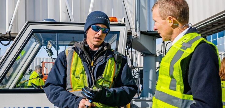 a man in safety vests talking to another man