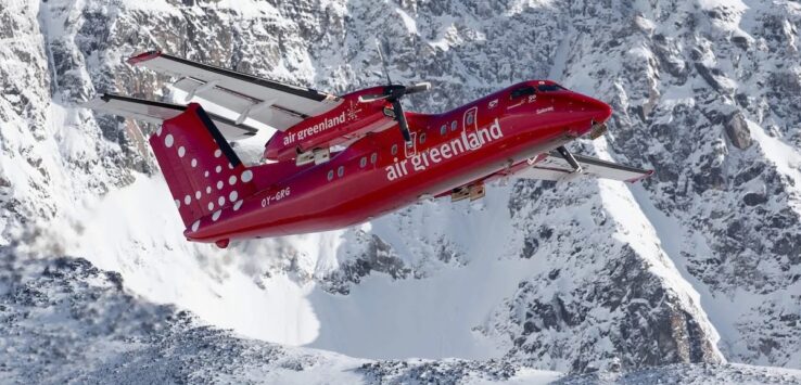 a red plane flying over snowy mountains