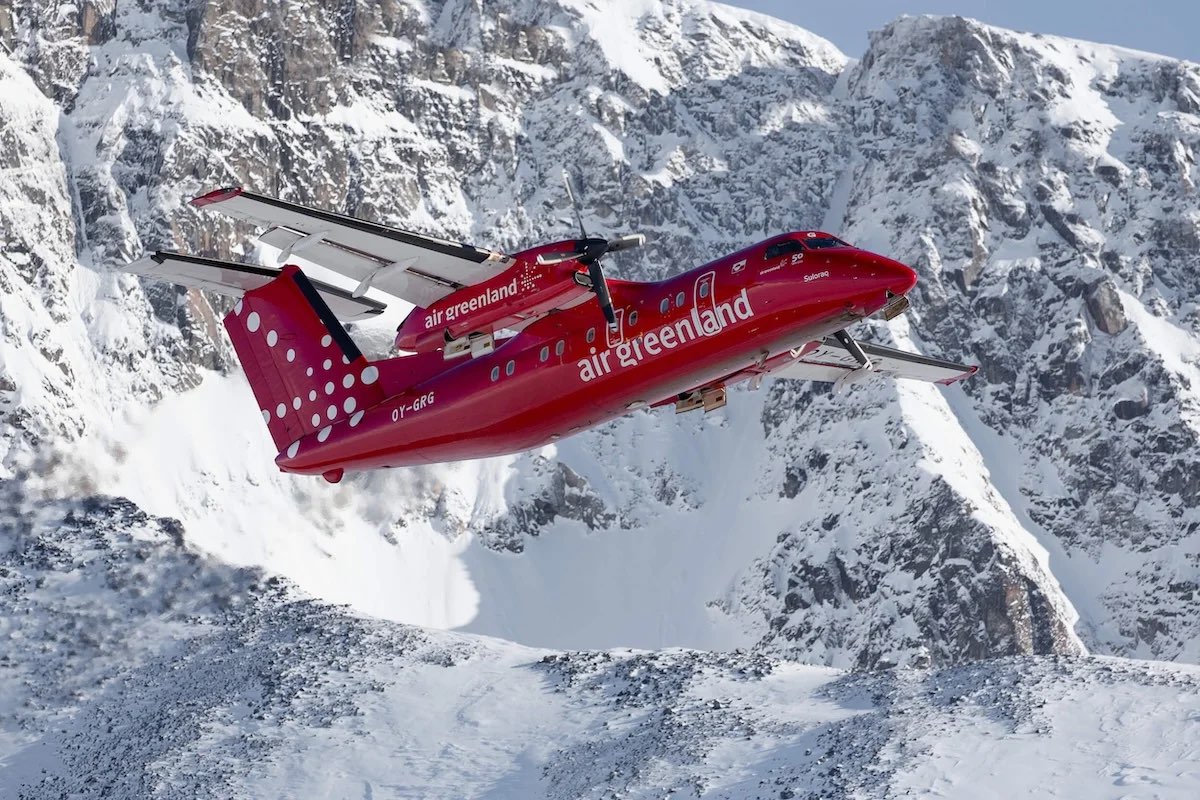 a red plane flying over snowy mountains