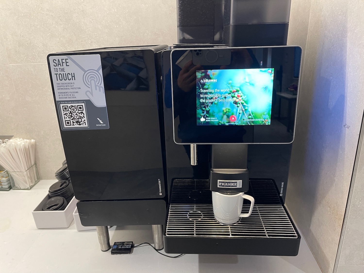 a coffee machine with a screen and a cup on the shelf