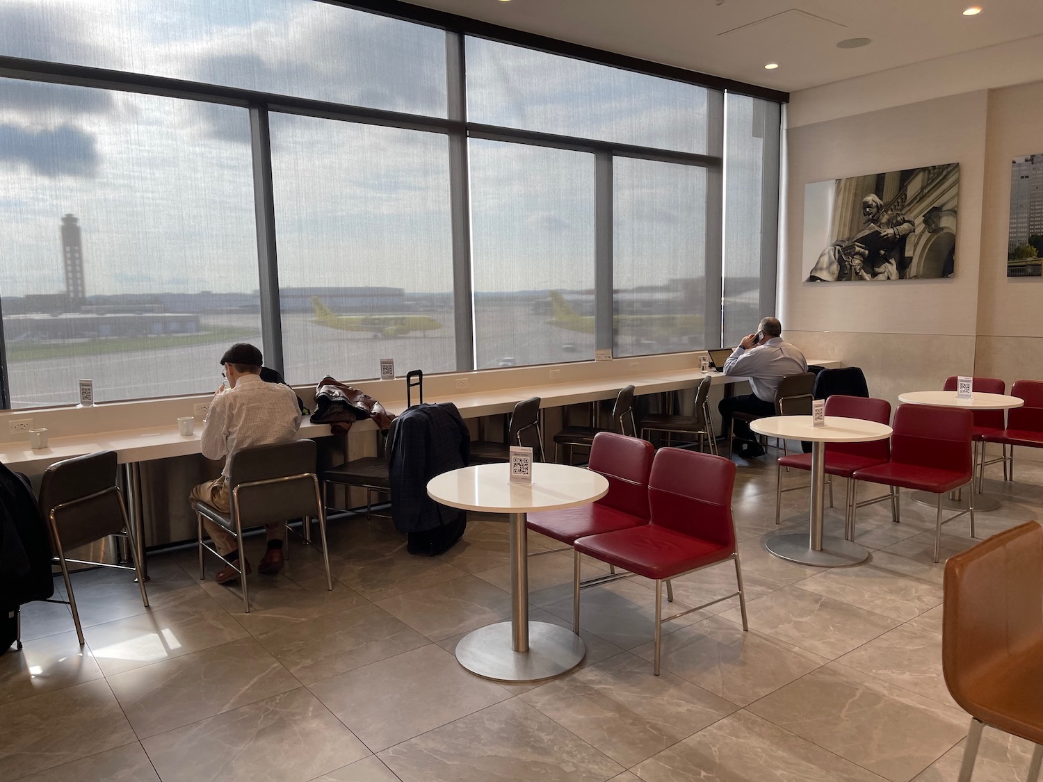 people sitting at tables in a room with large windows