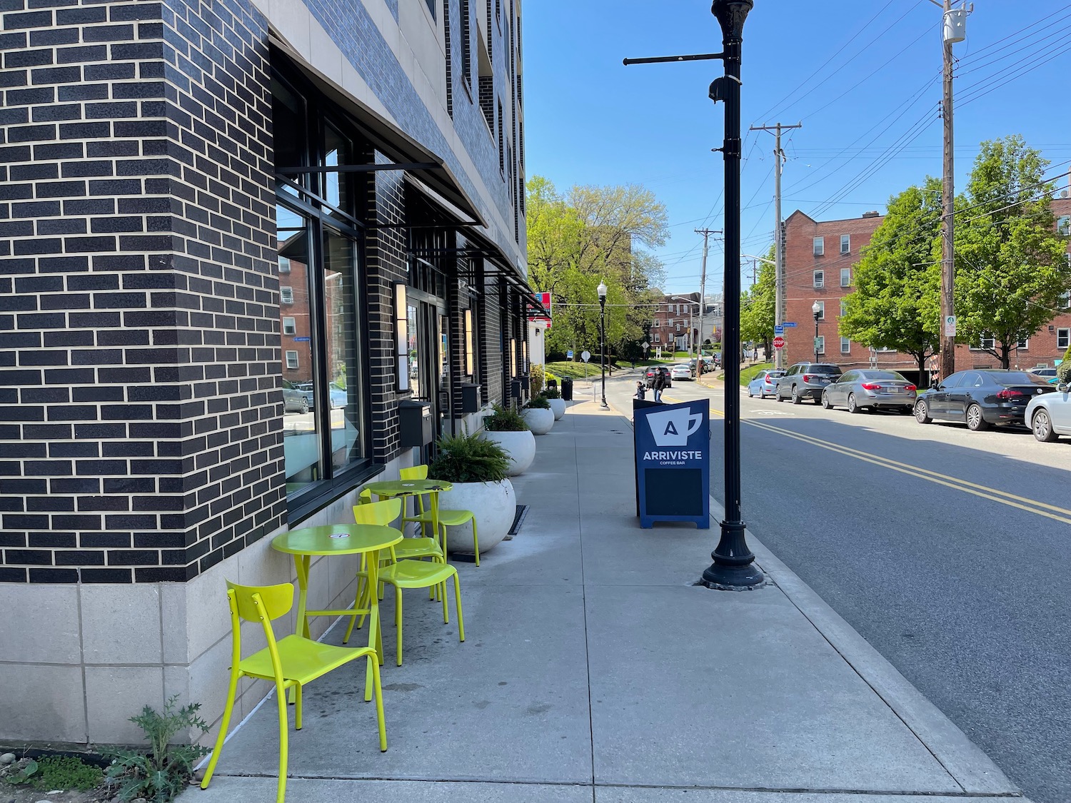 a sidewalk with yellow chairs and a sign on the side