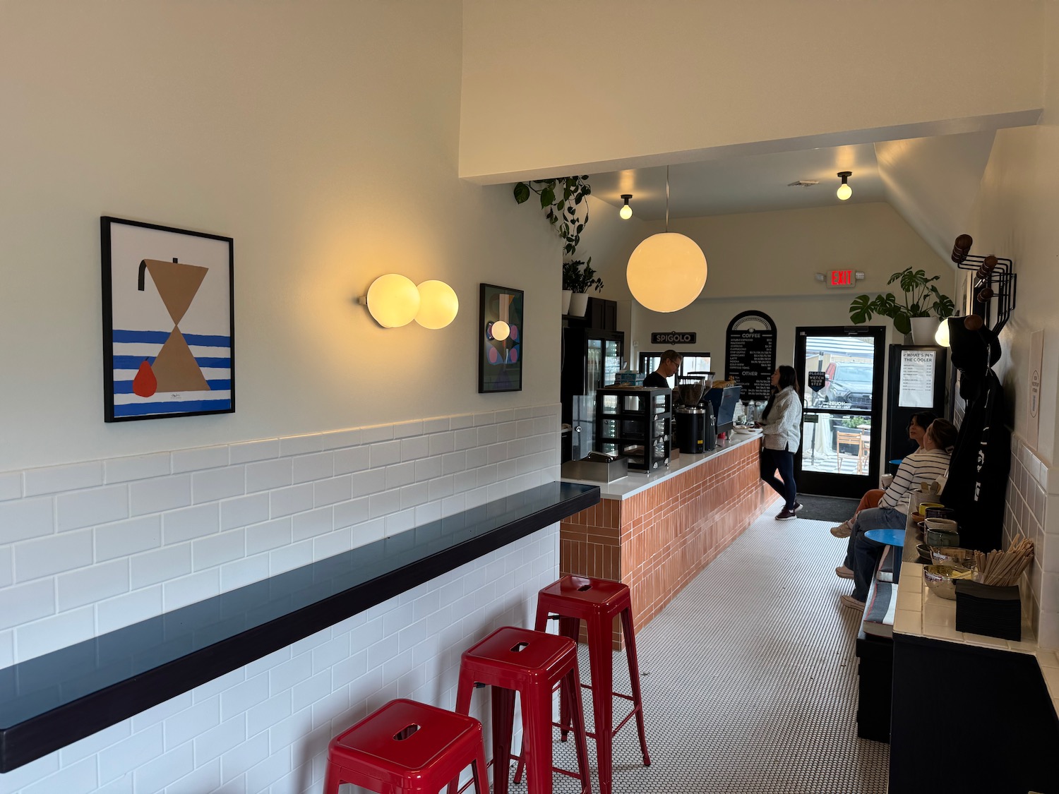 a bar with red stools and a couple people in the background
