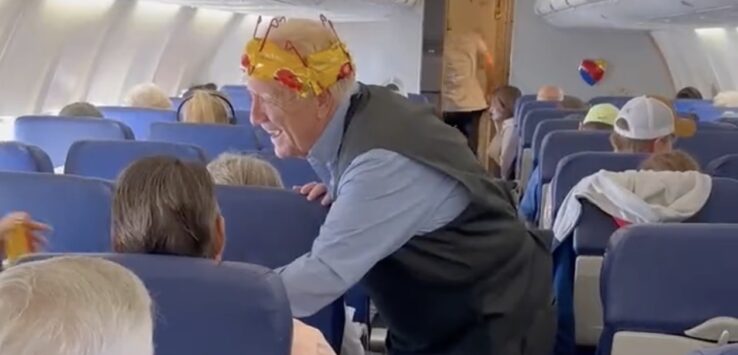 an older man wearing a crown on a plane
