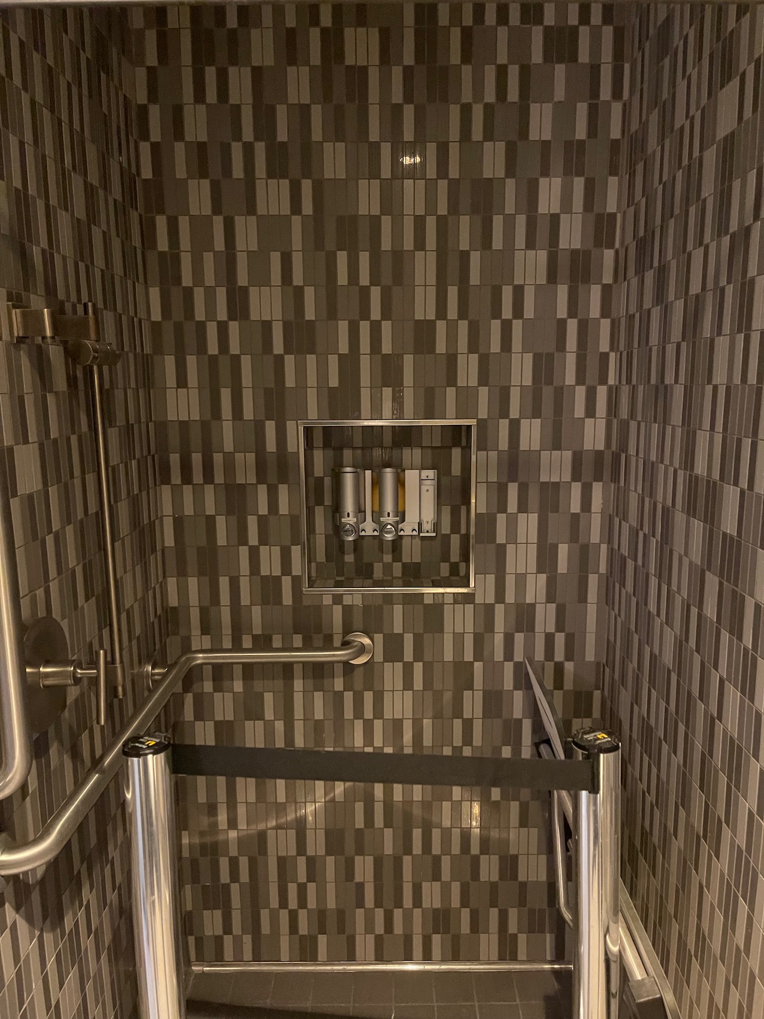 a shower with a tile wall and a metal frame
