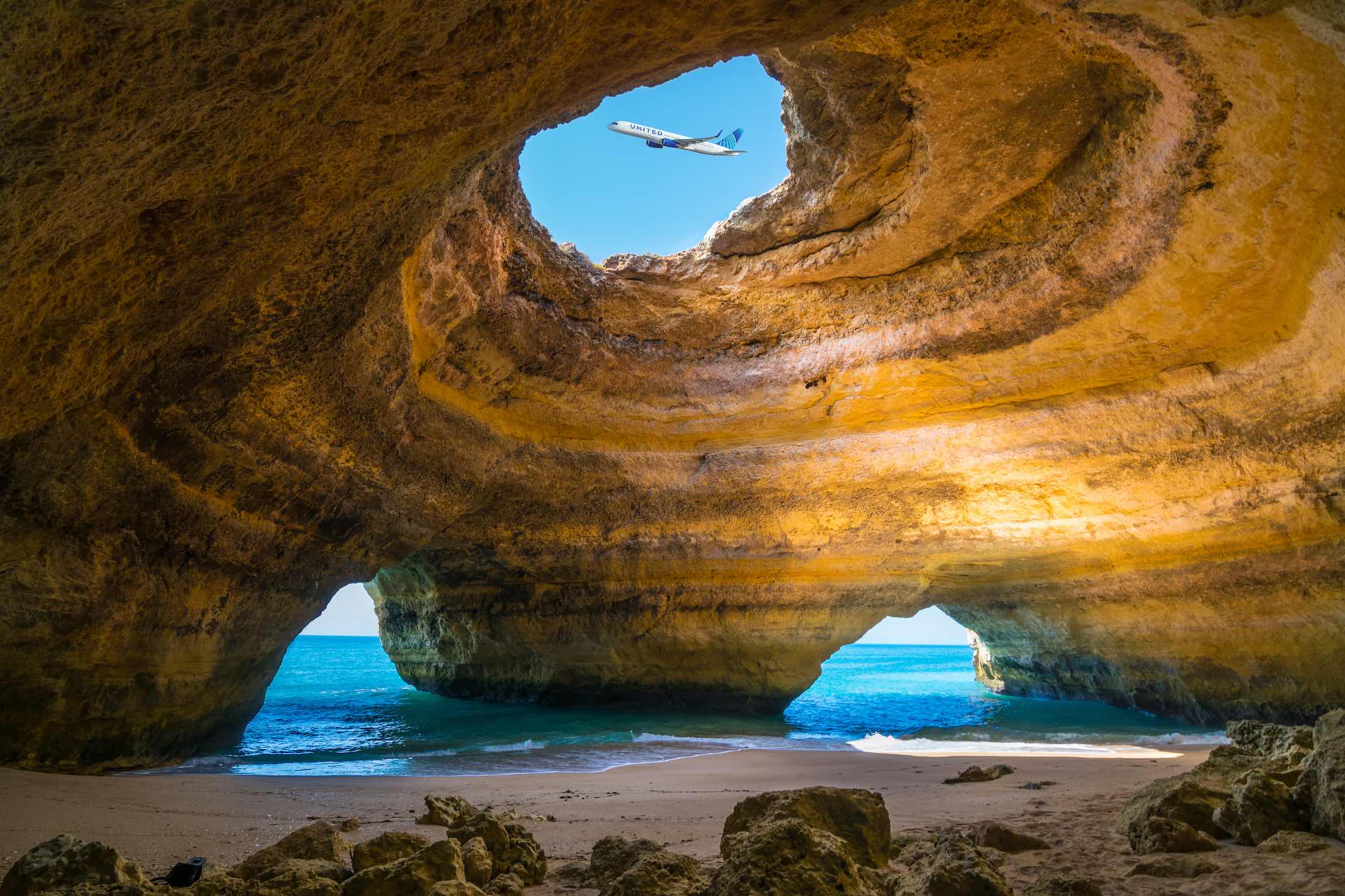 an airplane flying over a cave on a beach