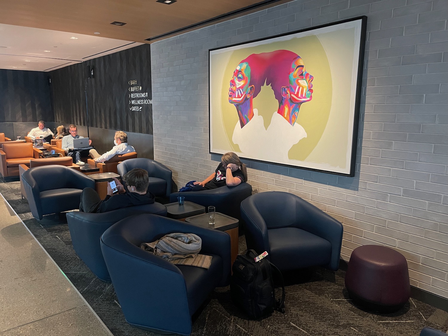 a group of people sitting in a room with chairs and a large picture on the wall