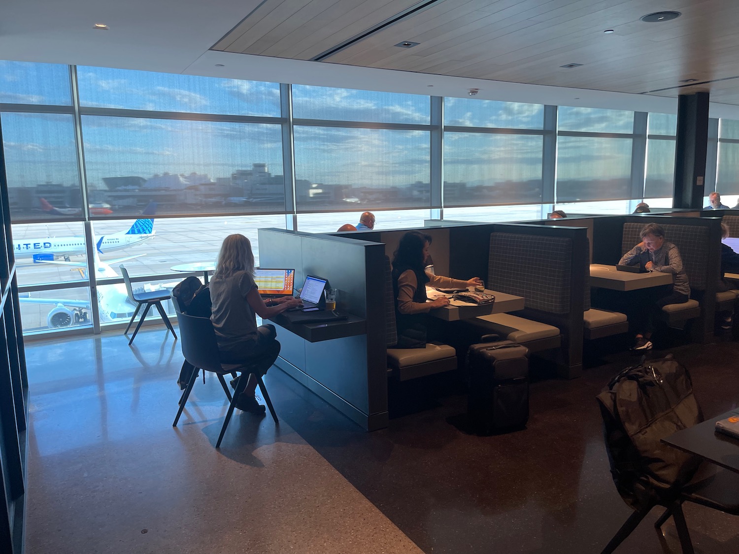 people sitting at tables in a room with windows and people sitting at tables