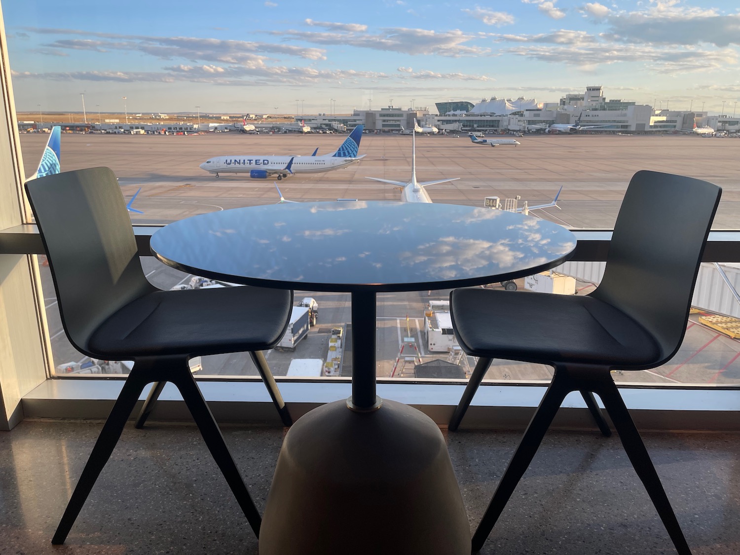 a table and chairs in front of a window with planes in the background